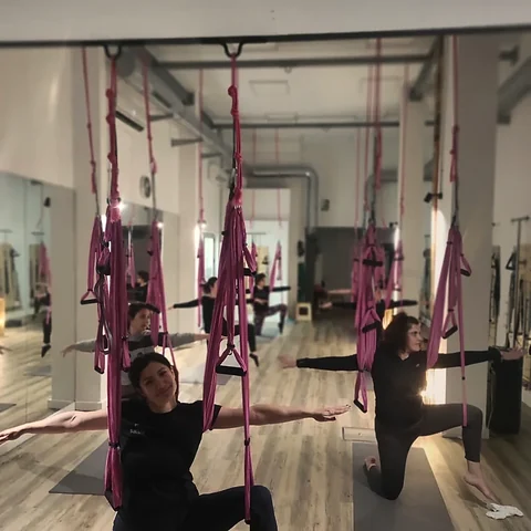 Alumna en una postura de AeroYoga con la pierna apoyada en la hamaca de tela