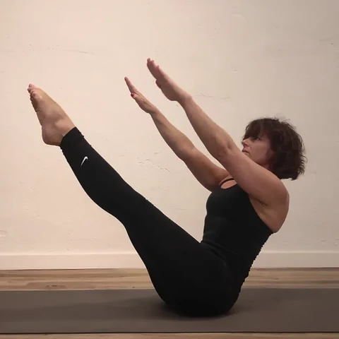 Alicia Sanz en una postura de Pilates sobre la colchoneta, con las piernas y los brazos extendidos en V